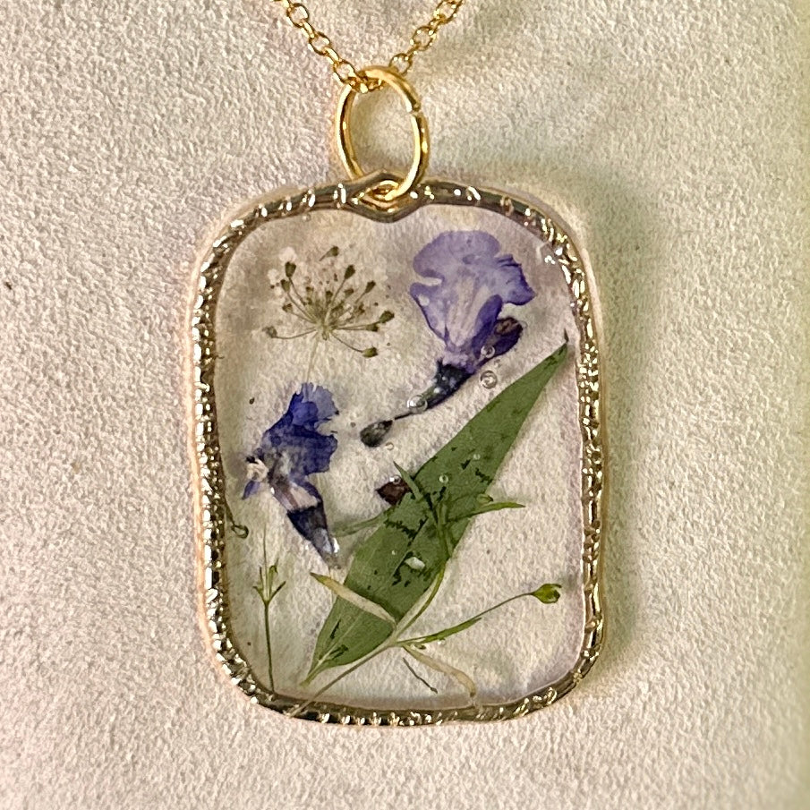 Gold-framed botanical necklace (violet, green, and white)