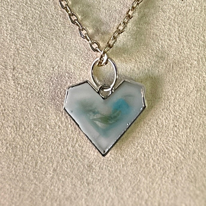 Silver-framed heart necklace with blue and green botanicals in white resin