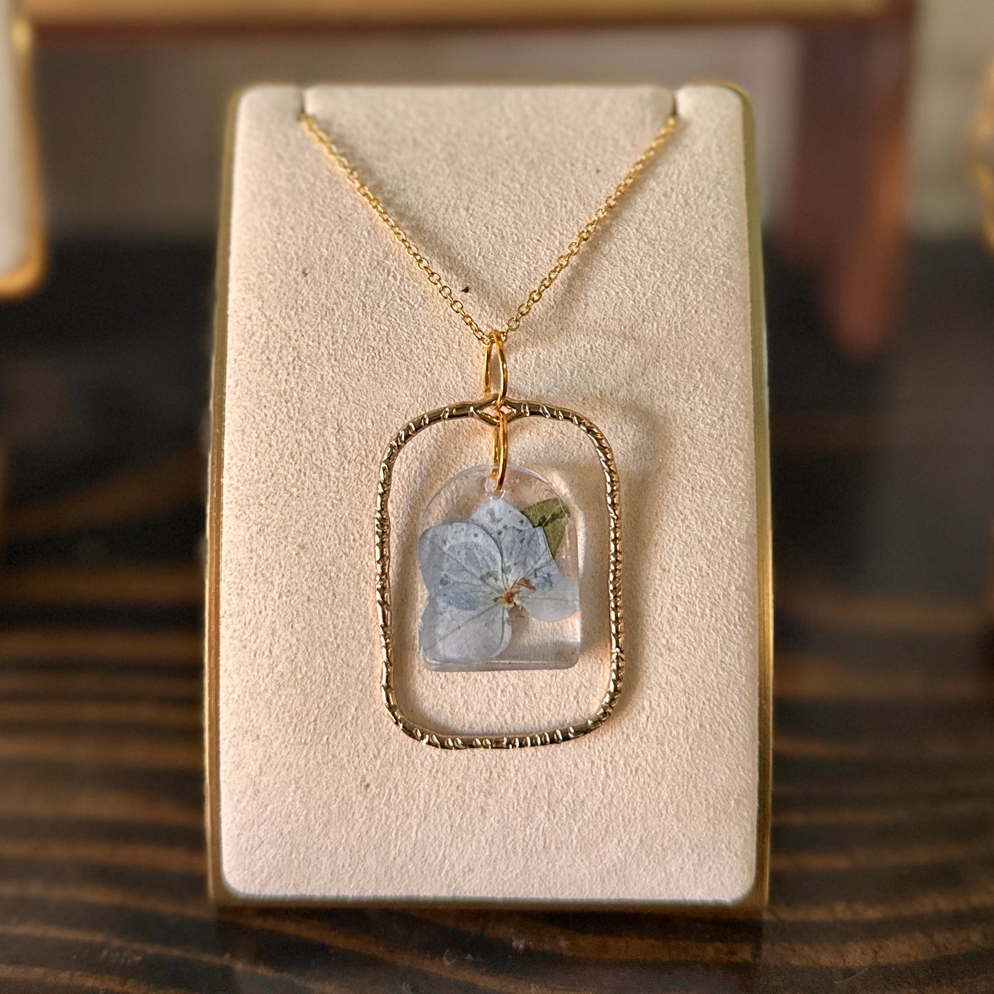 Gold-framed botanical necklace with blue flower