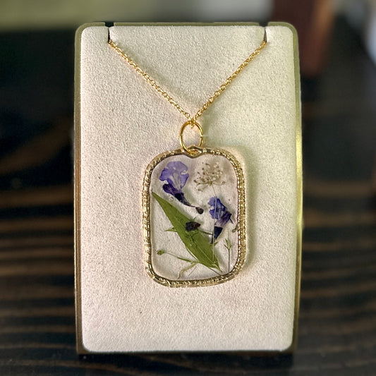 Gold-framed botanical necklace (violet, green, and white)