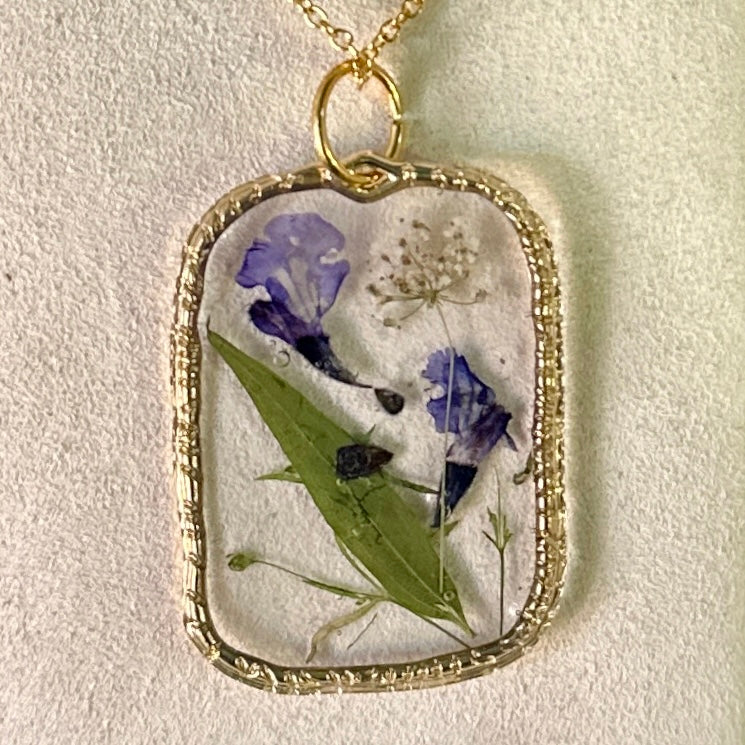 Gold-framed botanical necklace (violet, green, and white)