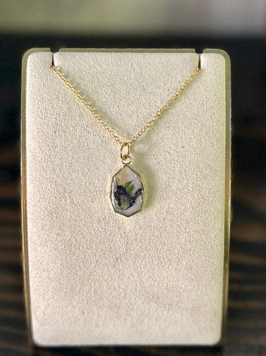 Gold-framed necklace with violet and green botanicals in white resin