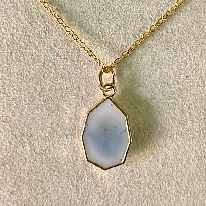 Gold-framed necklace with violet and green botanicals in white resin