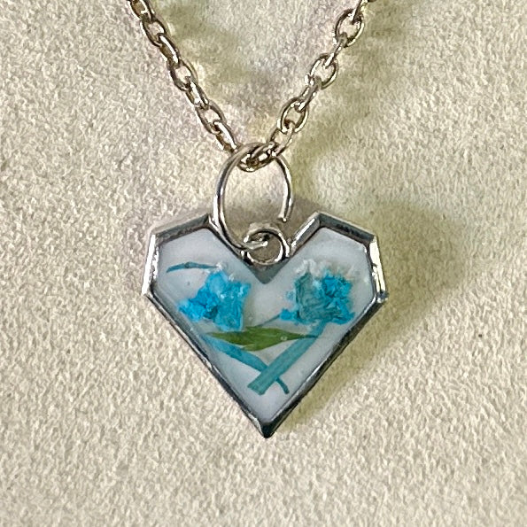 Silver-framed heart necklace with blue and green botanicals in white resin
